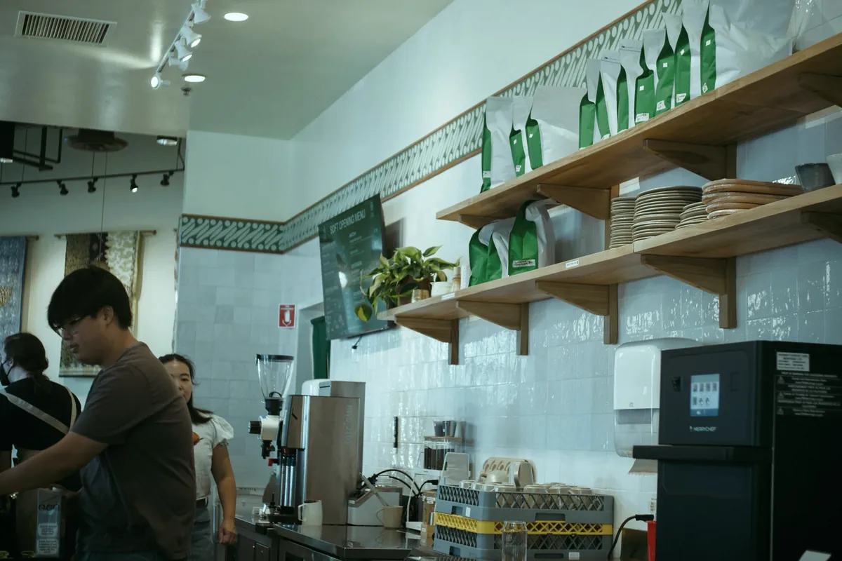 Barra de una cafetería con estanterías y máquina de café