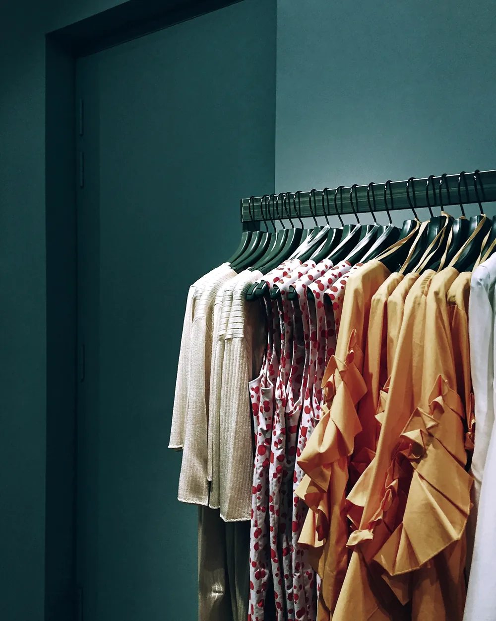 Prendas de colores colgadas en un perchero de una tienda de ropa